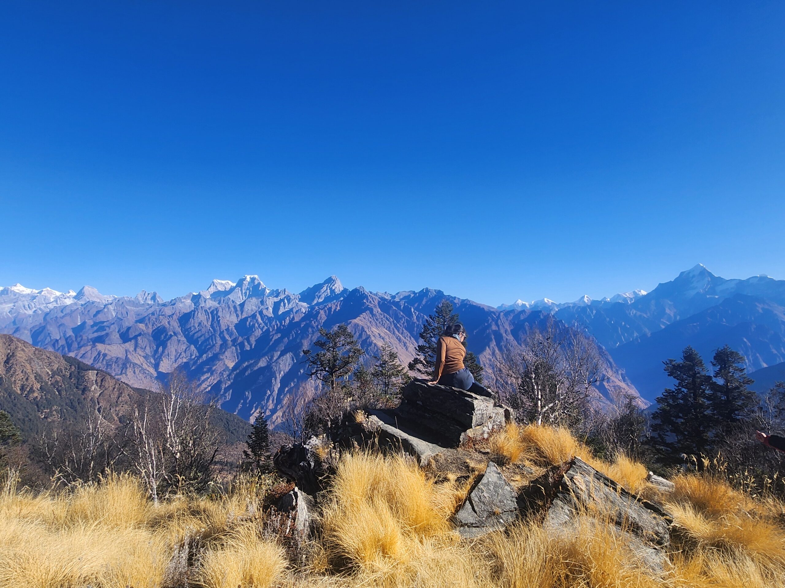 I sit on a rock overlooking a breathtaking panoramic view of the mountains.